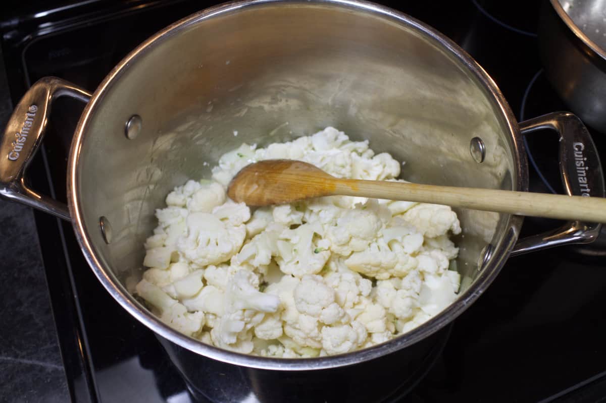 Cauliflower florets in a large stainless steel soup pot.