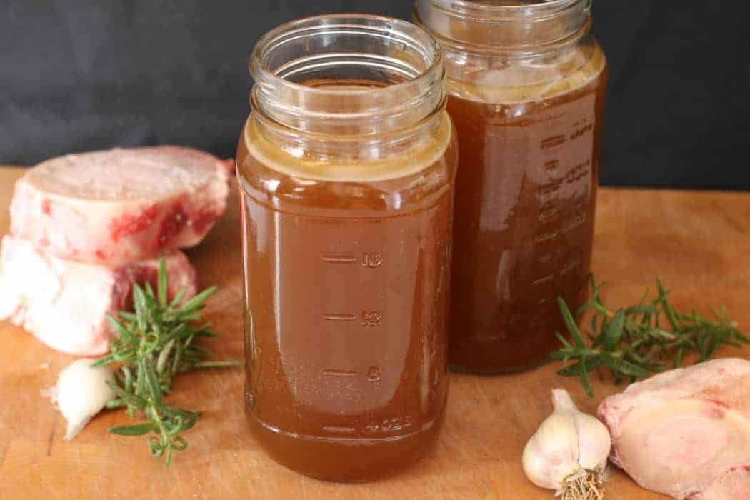 Two mason jars filled with homemade beef stock. 