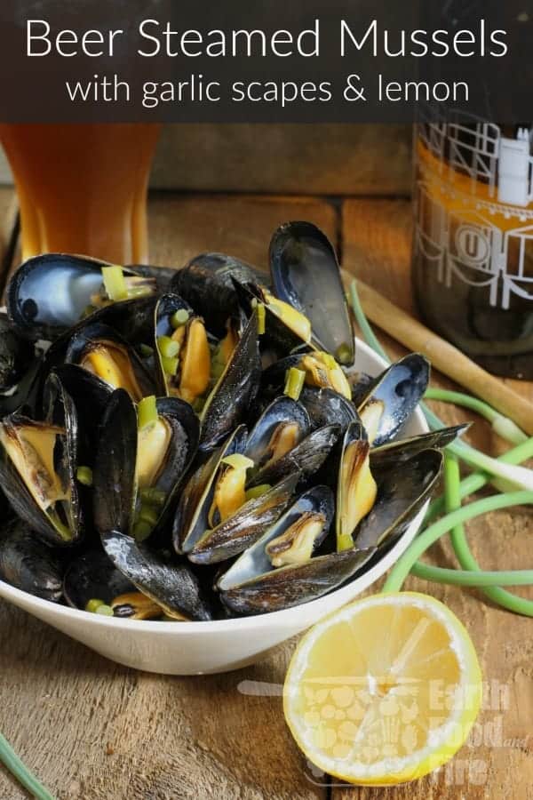 Beer steamed mussels with garlic scapes and lemon served in a white bowl