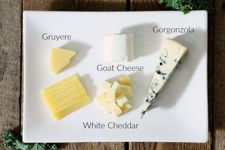 a selection of cheeses on a white plate with labels to identify each