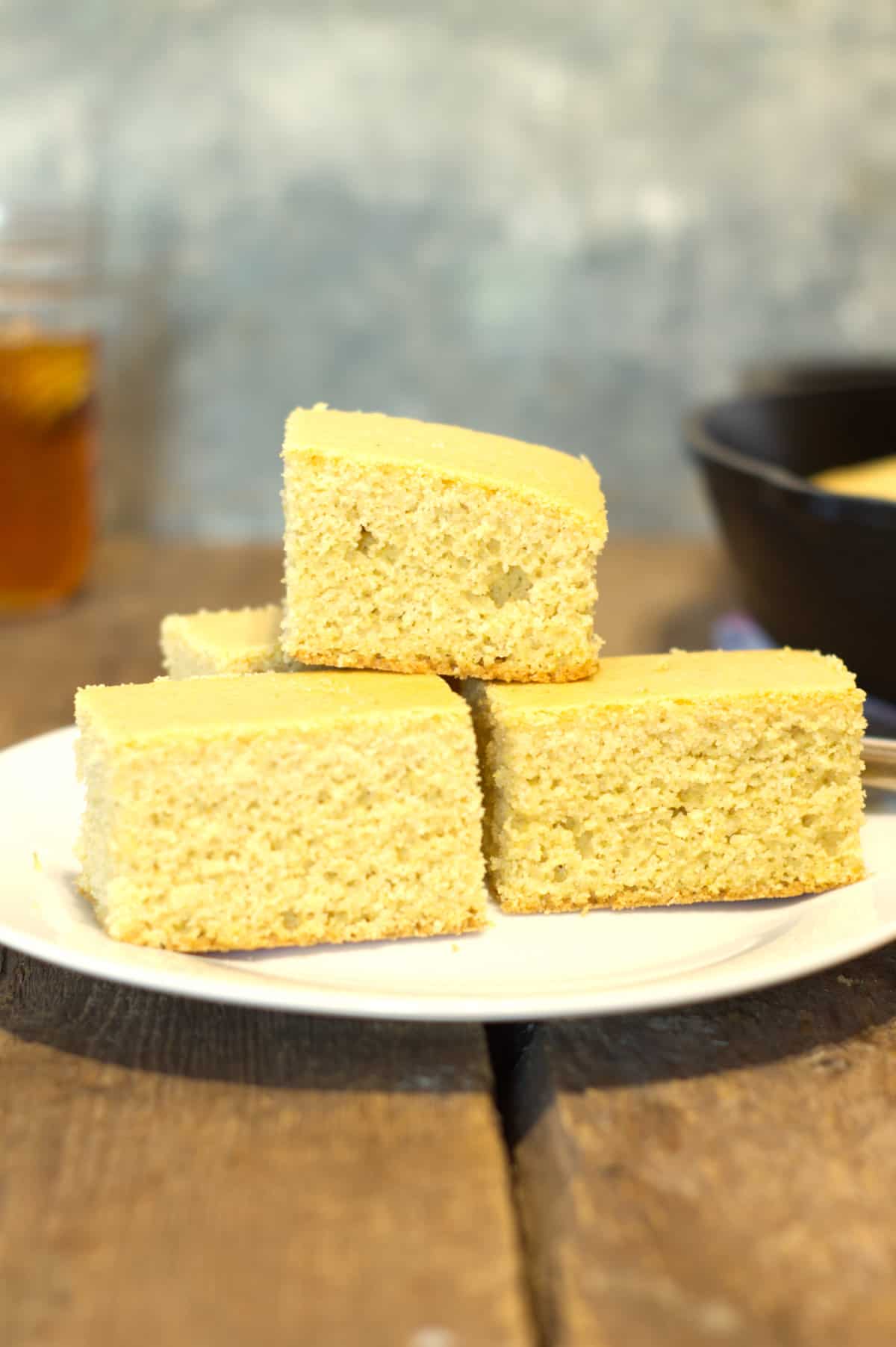 vertical image of square pieces of dairy free corn bread stacked on a white plate