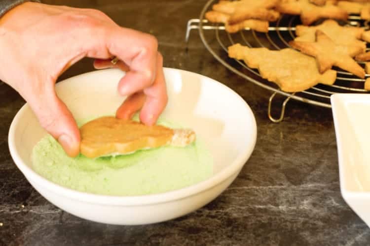 dipping the iced cookies into the pastel colored sugar