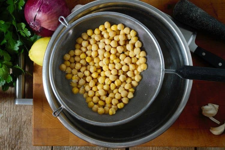 canned chickpeas draining over a metal bowl