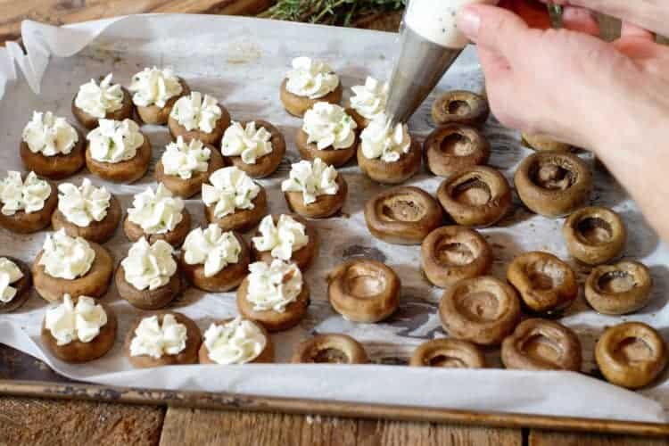 piping roast garlic flavored goat cheese into roasted mushroom caps