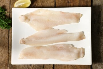 three pieces of fresh haddock on a white plate