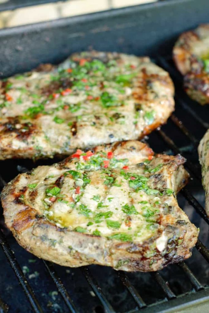 grilled pork chops brushed with chimichurri on a BBQ grill