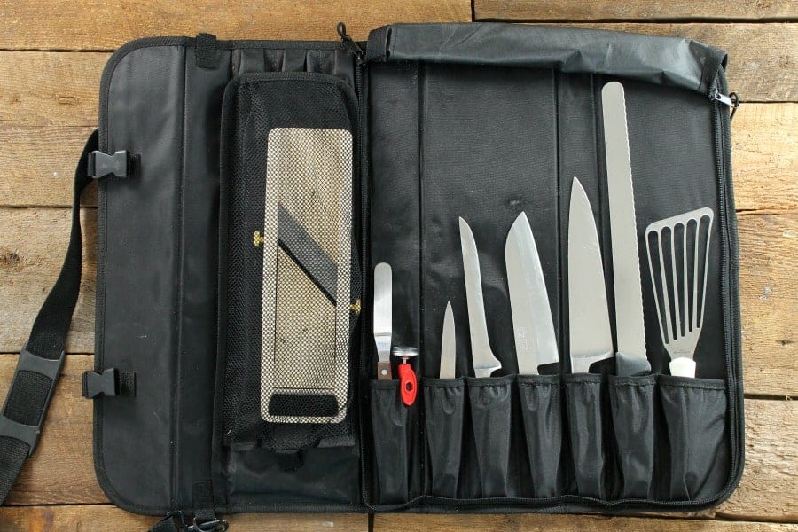 A knife roll filled with different types of kitchen knives on a wooden tabletop