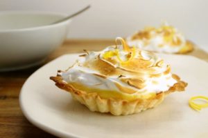 2 lemon meringue tarts on plates