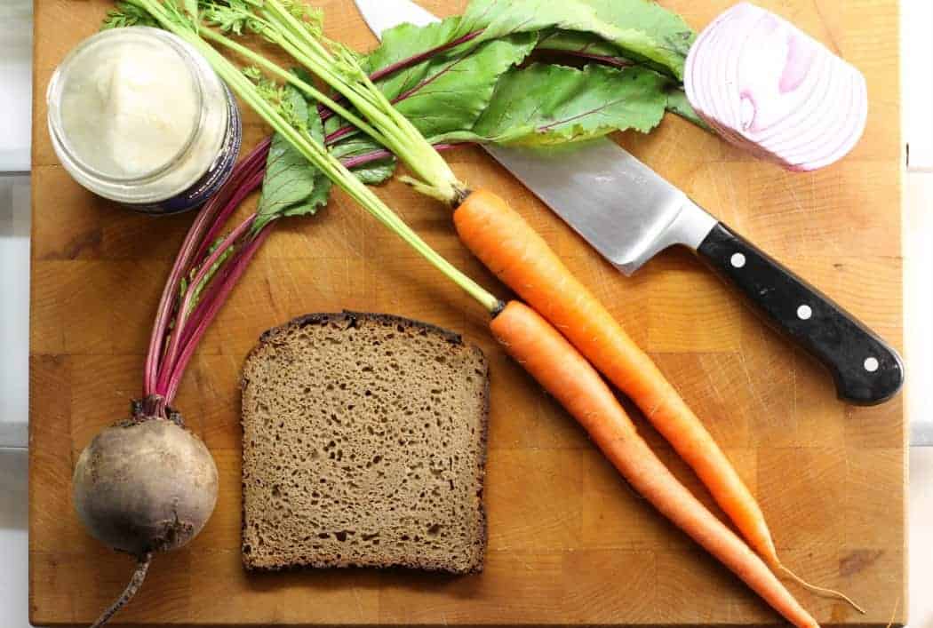 A European classic, this pickled herring sandwich, features dark rye bread, a beet and carrot slaw, red onion, and homegrown alfalfa sprouts! 