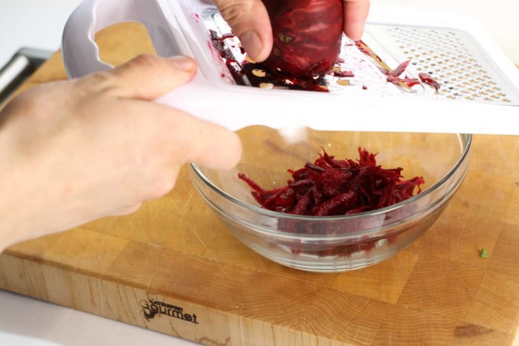 red beet being shredded on a handheld grater