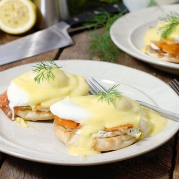 smoked salmon eggs benedict garnished with dill on a white plate