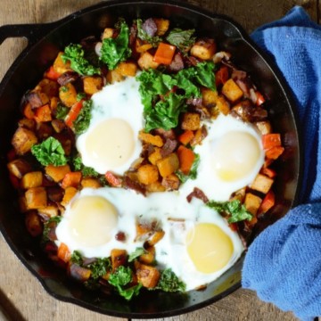 sweet potato hash with bacon, onion, bell pepper, kale, and eggs served in cast iron pan